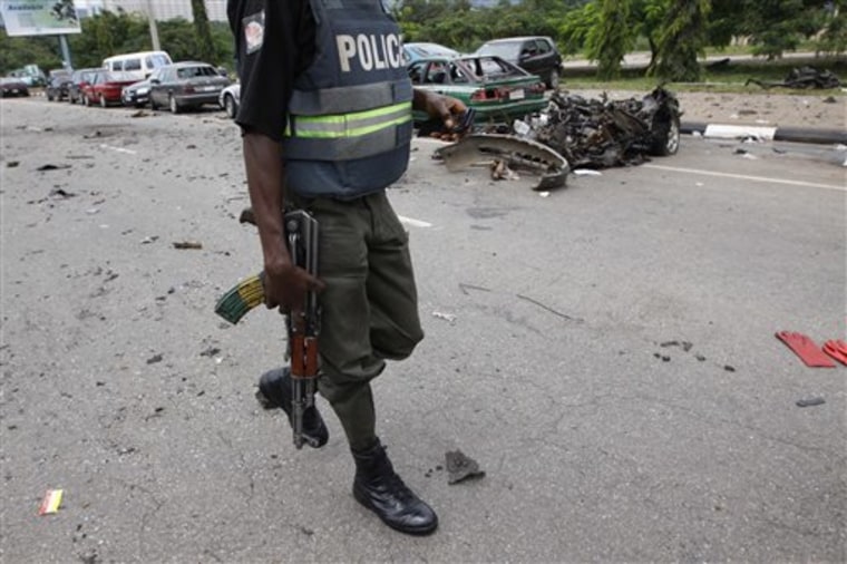 A Nigerian police officer walks past the burnt out shell of a car, after a car bomb exploded in Abuja, Nigeria, Friday, Oct 1, 2010. Two car bombs blew up on as Nigeria celebrated its 50th independence anniversary, killing at least seven people in an unprecedented attack on the capital by suspected militants from the country's oil region. (AP Photo/Sunday Alamba)